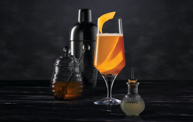 Cocktail mixing tools surrounding a Midnight Manhattan on a dark surface